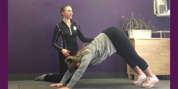 Woman in downward dog while another teaches